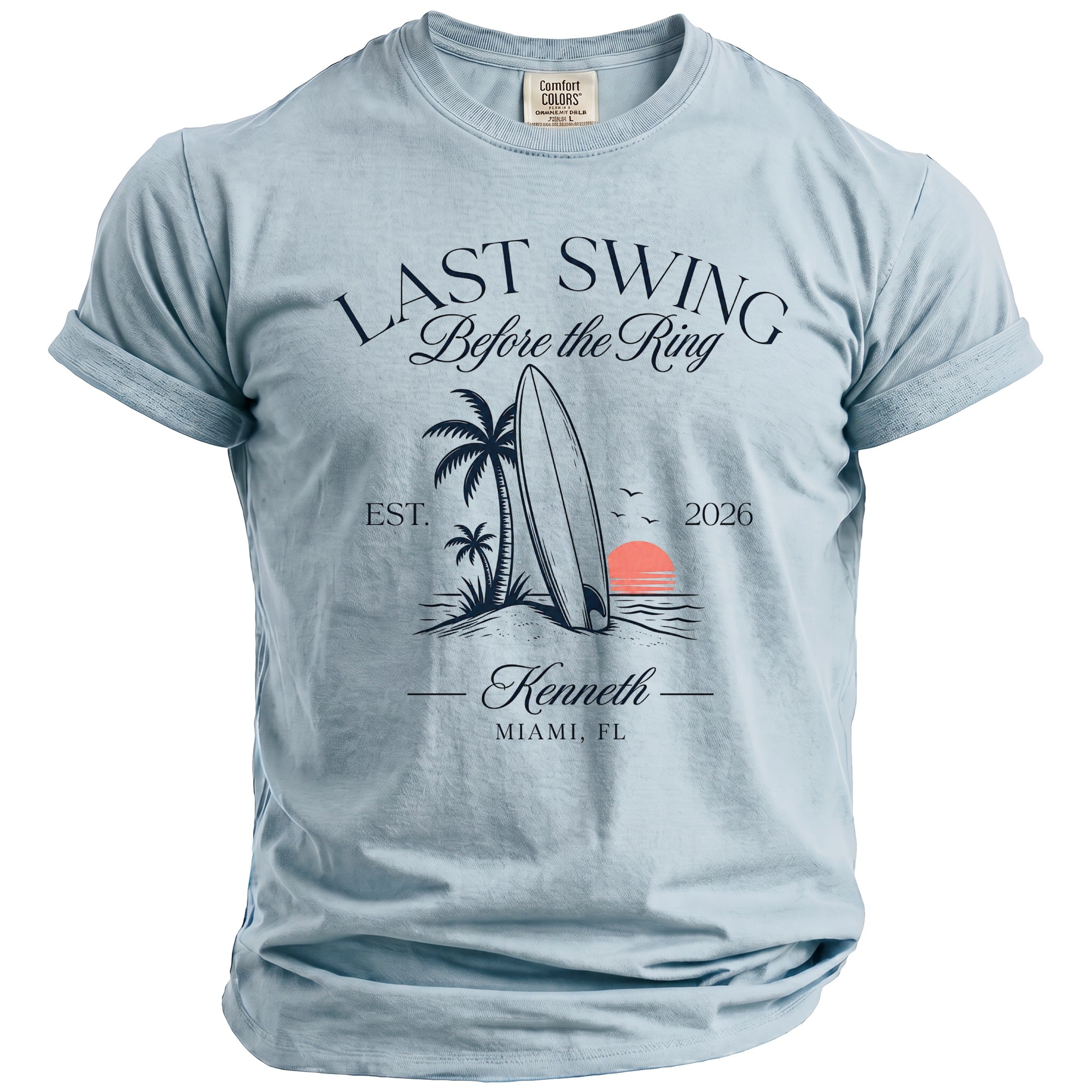 Light blue t-shirt with "LAST SWING Before the Ring" graphic, surfboard, palms, and sunset.