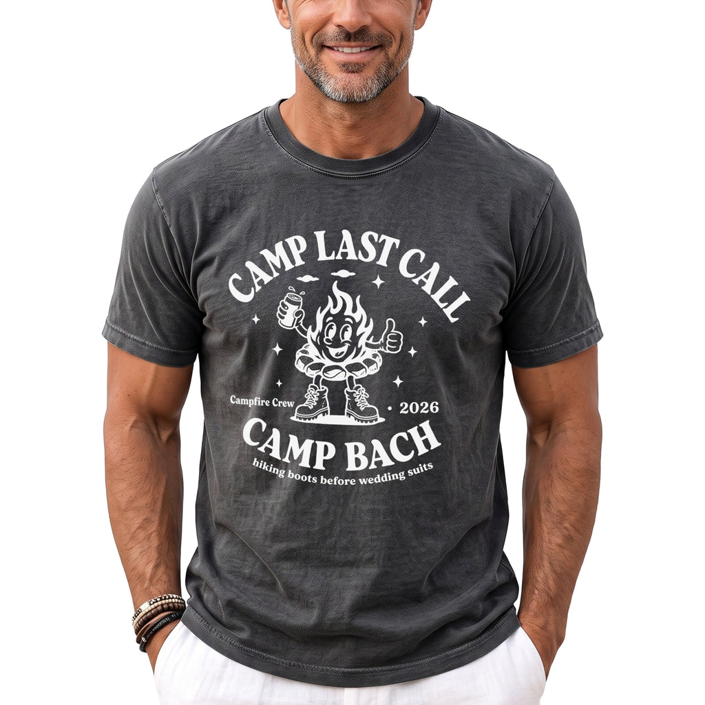 A man wearing a dark gray t-shirt with a white graphic featuring a cartoon campfire and text reading Camp Bach.