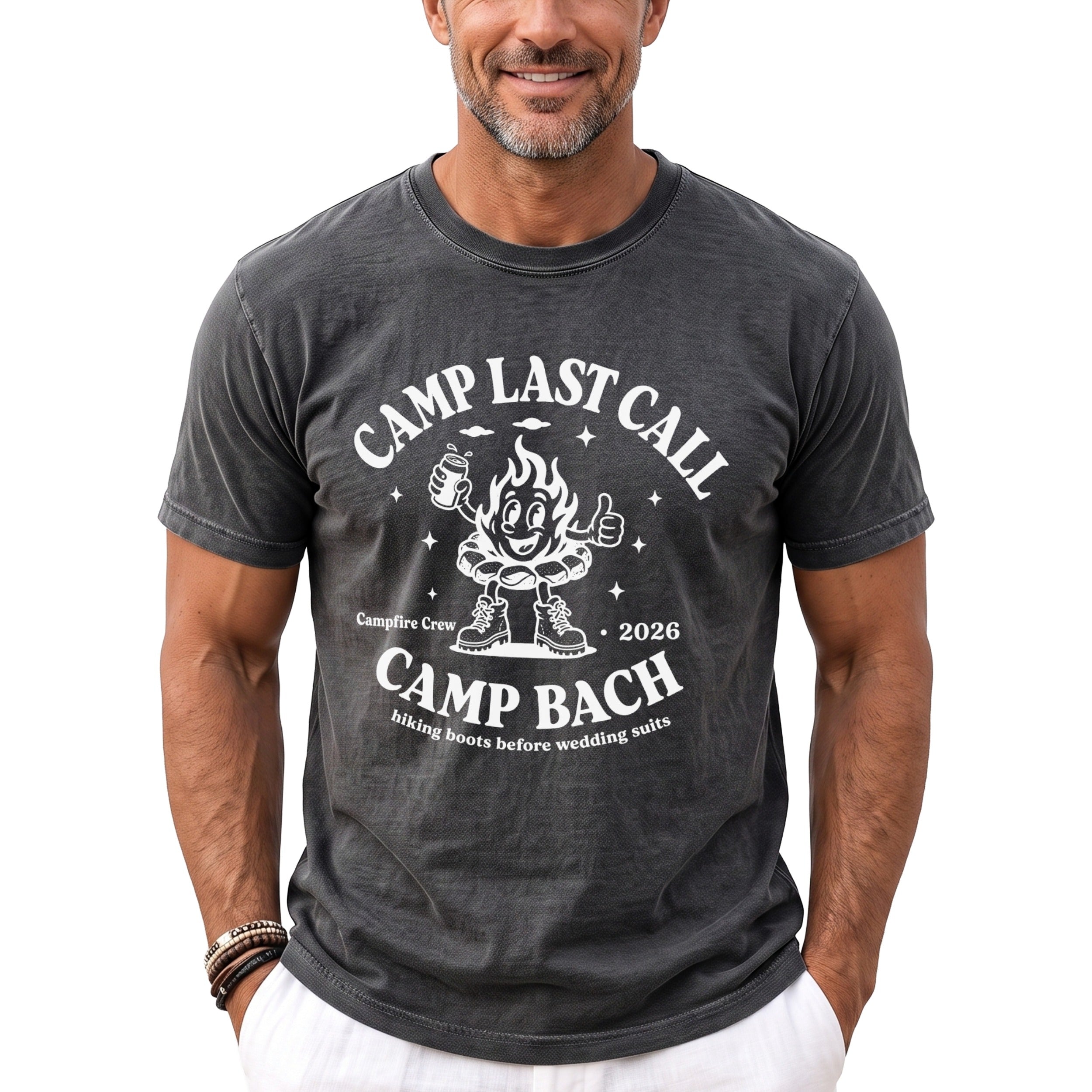 A man wearing a dark gray t-shirt with a white graphic featuring a cartoon campfire and text reading Camp Bach.