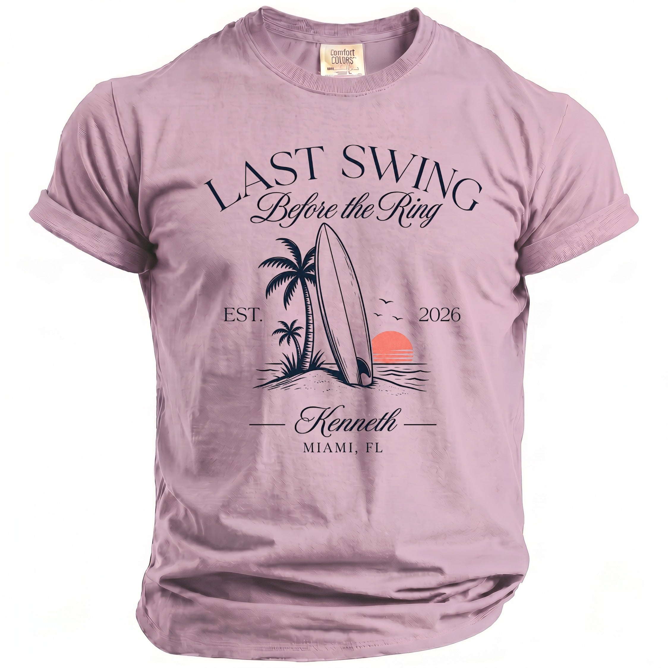 Pink t-shirt with "Last Swing Before the Ring" graphic featuring a surfboard, palm trees, and sunset.