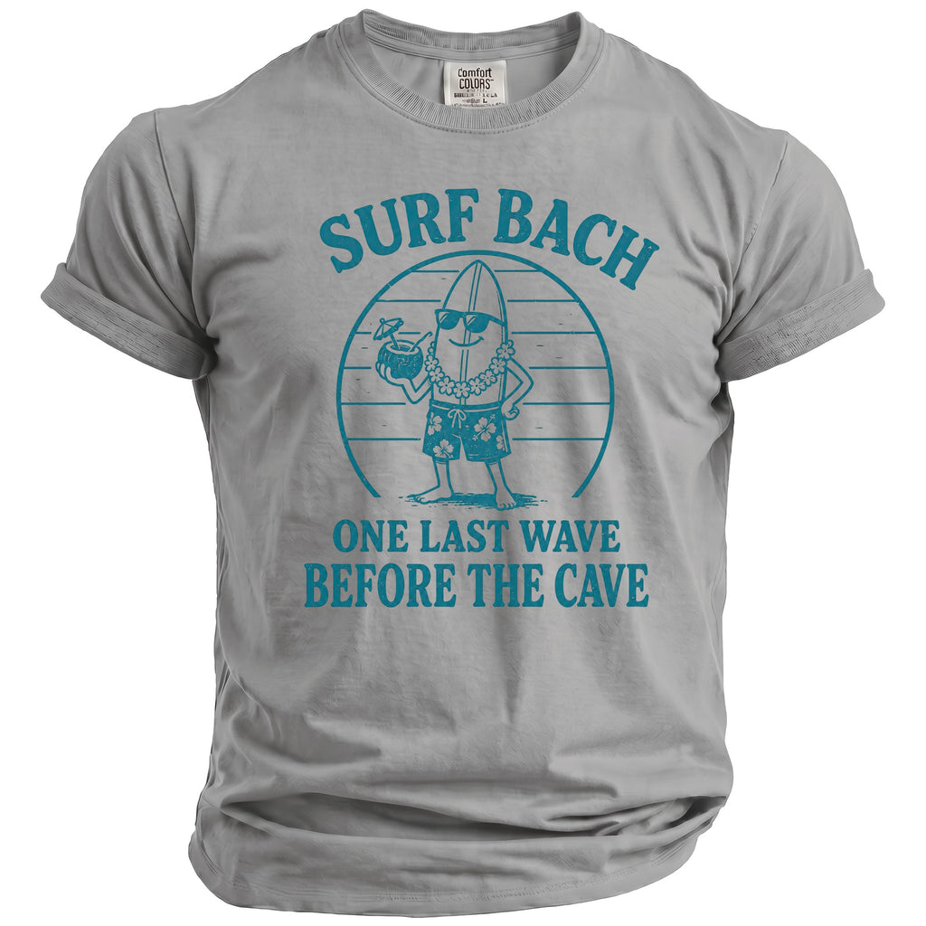Grey t-shirt with cartoon surfboard wearing sunglasses, lei, and shorts, with text "SURF BACH ONE LAST WAVE BEFORE THE CAVE".
