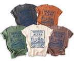 Five t-shirts in black, orange, green, cream, and brown featuring blue dragon graphic.