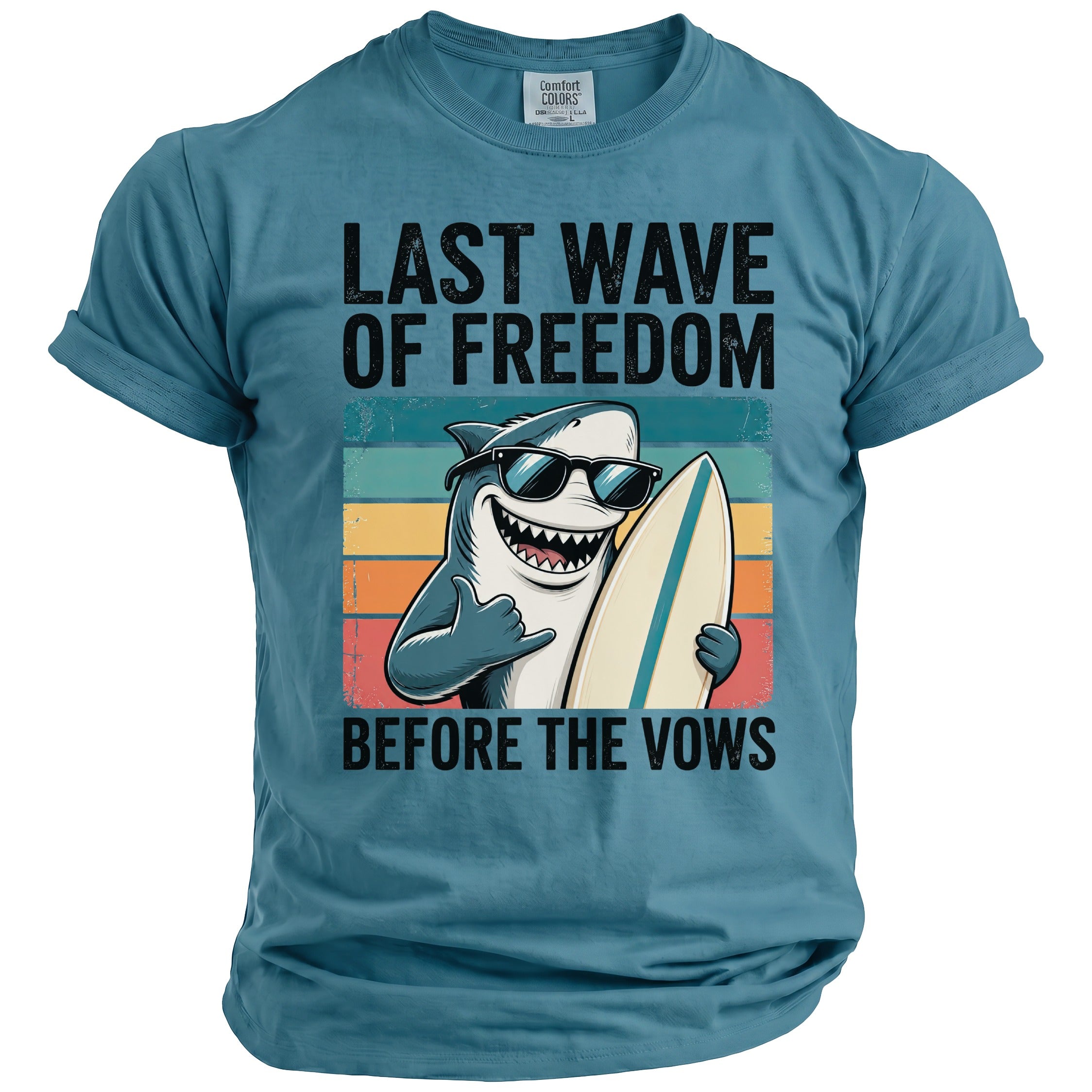 Blue t-shirt with a cartoon shark holding a surfboard and text "LAST WAVE OF FREEDOM BEFORE THE VOWS".