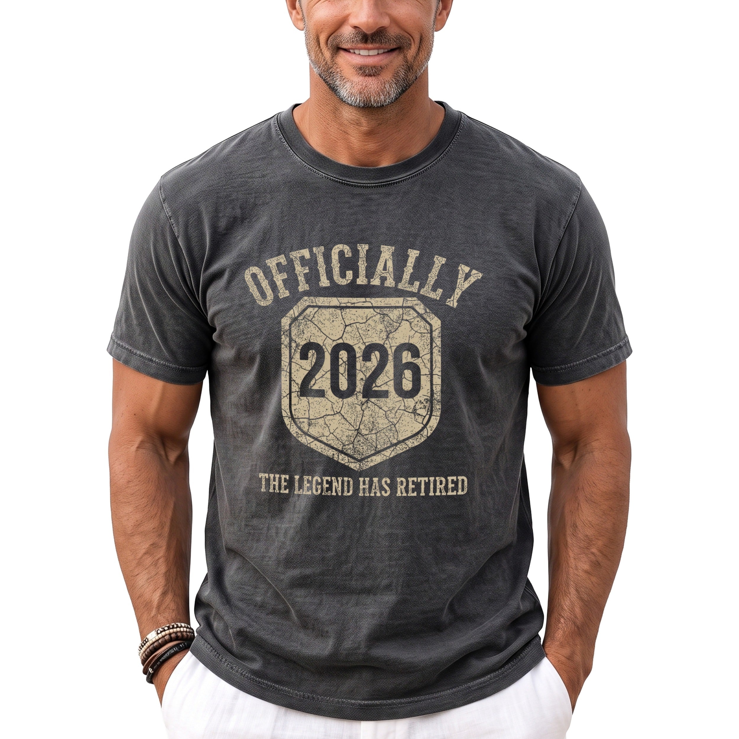 Dark grey t-shirt with "Officially 2026 The Legend Has Retired" text and shield graphic.