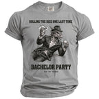 Grey t-shirt graphic of a dragon with a hat holding cards and drink, reads "Bachelor Party".