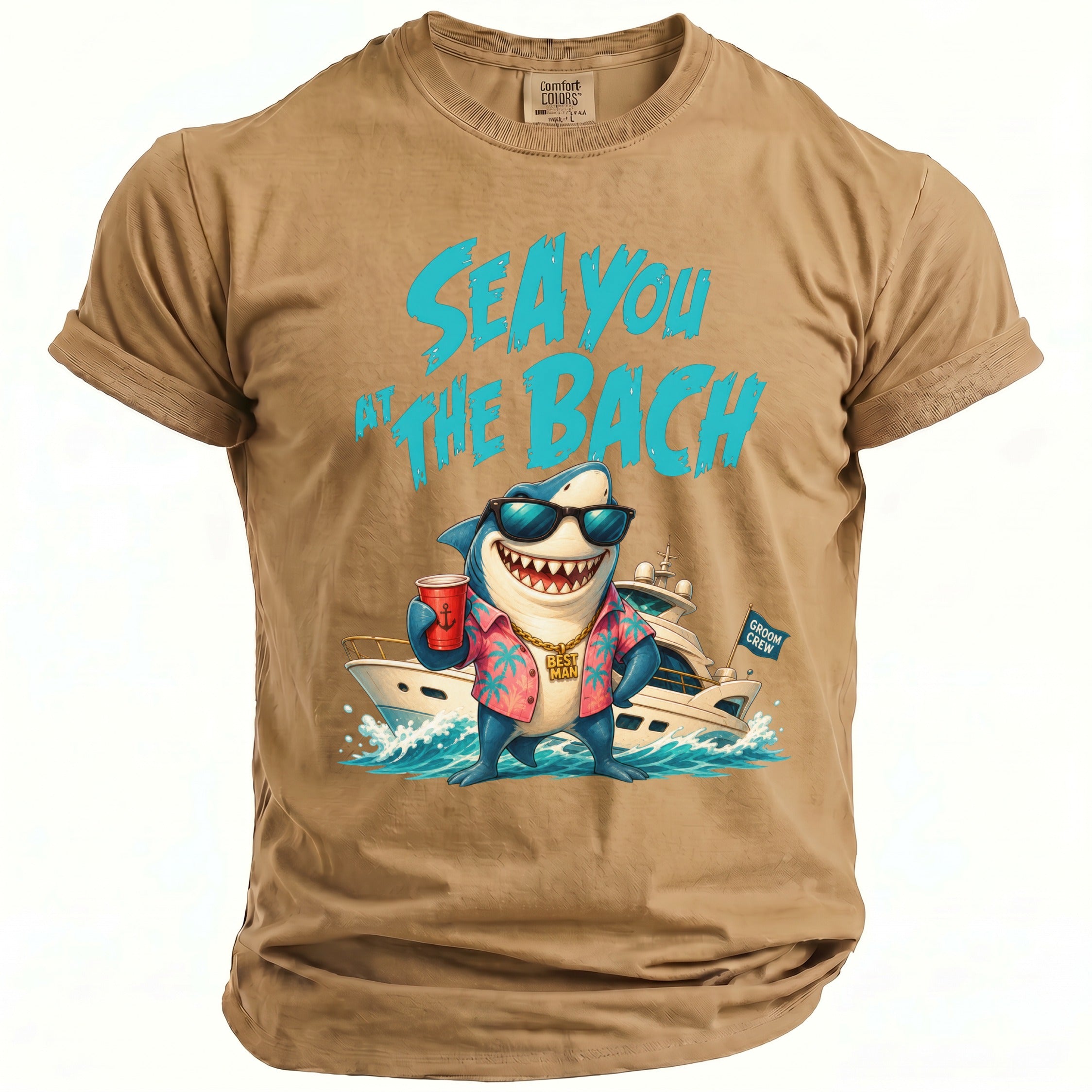 A beige t-shirt featuring a cartoon shark wearing sunglasses and a tropical shirt in front of a yacht, with blue text that reads Sea You at the Bach.