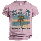 Pink t-shirt with "Bachelor Beach Club Groom's Last Wave 2026" text and beach graphic.
