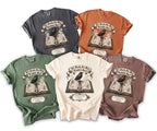 Five t-shirts in different colors featuring a crow on an open book with text 'Til Death, Our Most Faithful Spell'.