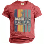 Red T-shirt with "Bachelor Beach Club" and "Groom's Beach Weekend - 2026" text.
