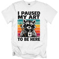 White t-shirt with a raccoon wearing sunglasses holding a paintbrush and coffee mug.