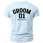 Light blue t-shirt with "GROOM 01" and "[NAME] - BACH 2026 - [CITY]" printed on back.