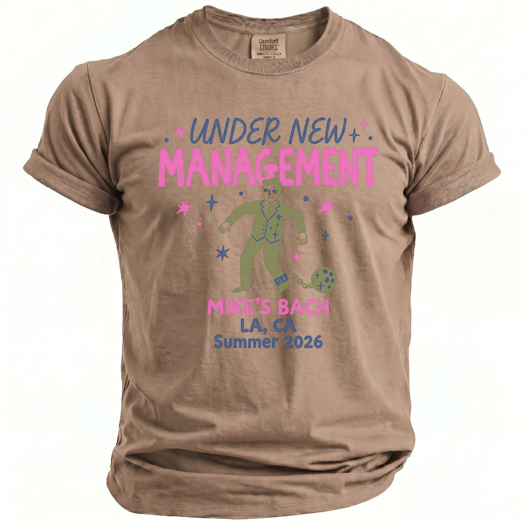 Brown t-shirt with graphic "Under New Management" and man in suit chained to ball.