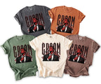 Five t-shirts in various colors, each with a devilish groom graphic and flaming text.