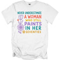 White t-shirt with text "Never underestimate a woman who still paints in her seventies".
