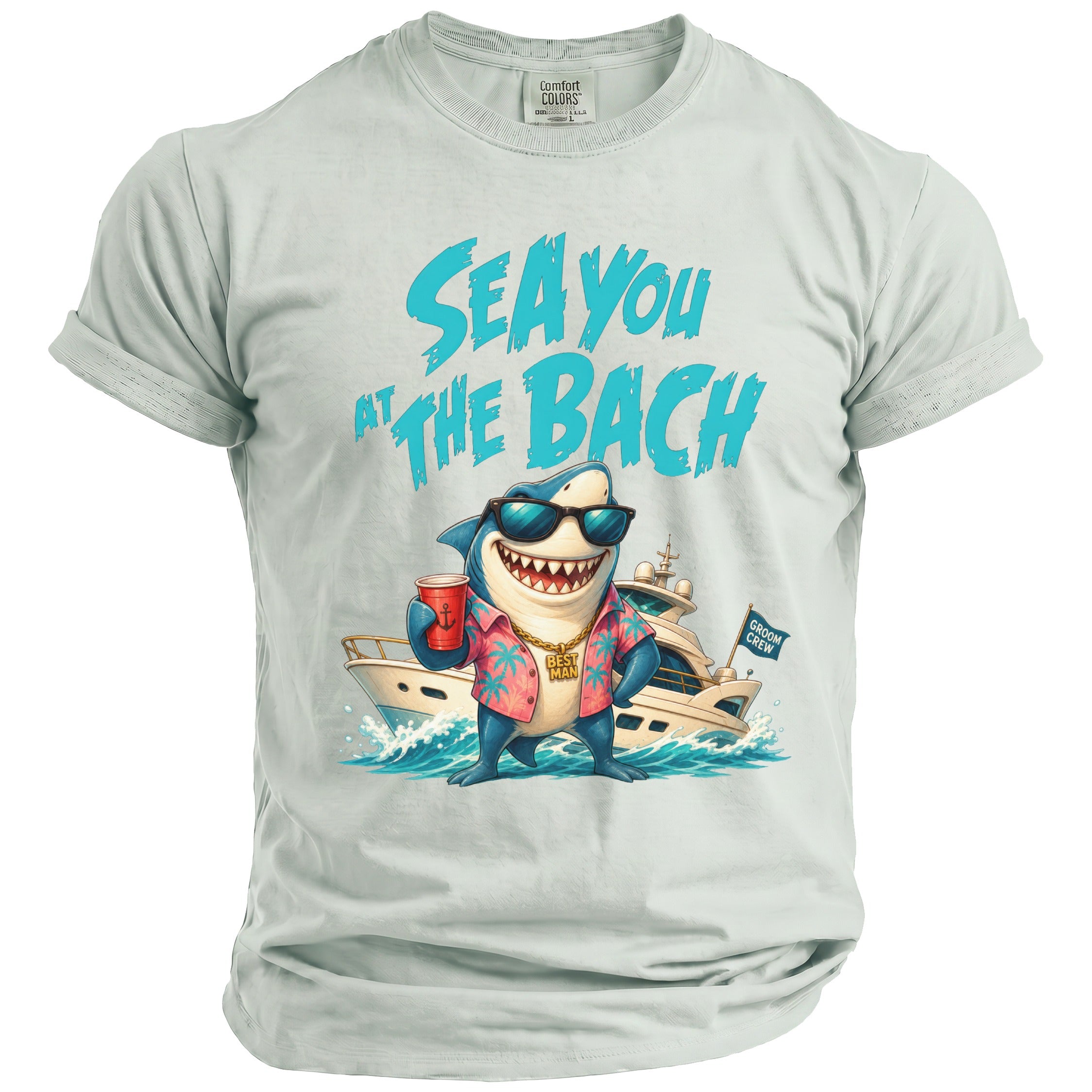 A light gray crewneck t-shirt featuring a graphic of a smiling shark in sunglasses, a pink tropical shirt, and a yacht with text reading SEA YOU AT THE BACH.