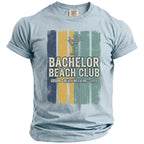 Light blue t-shirt with "Bachelor Beach Club Groom's Beach Weekend - 2026" graphic.