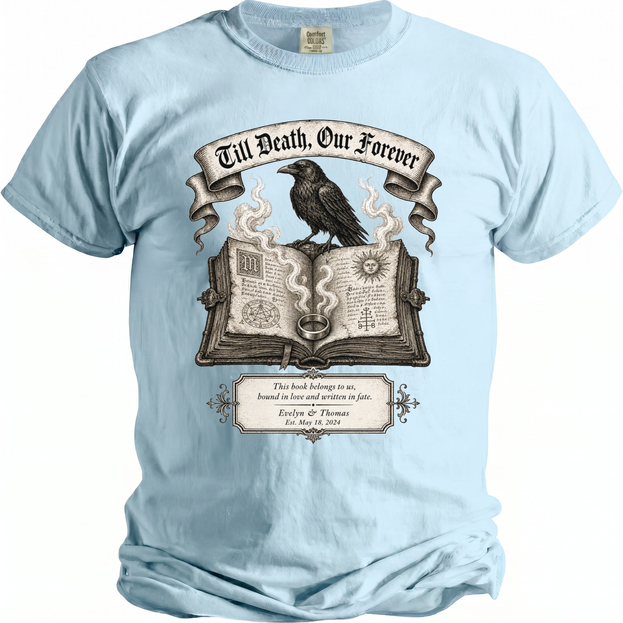 Light blue t-shirt with a graphic of an open book, a raven, and a ring.