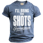 Blue t-shirt with white text reading "I'LL BRING THE SHOTS G