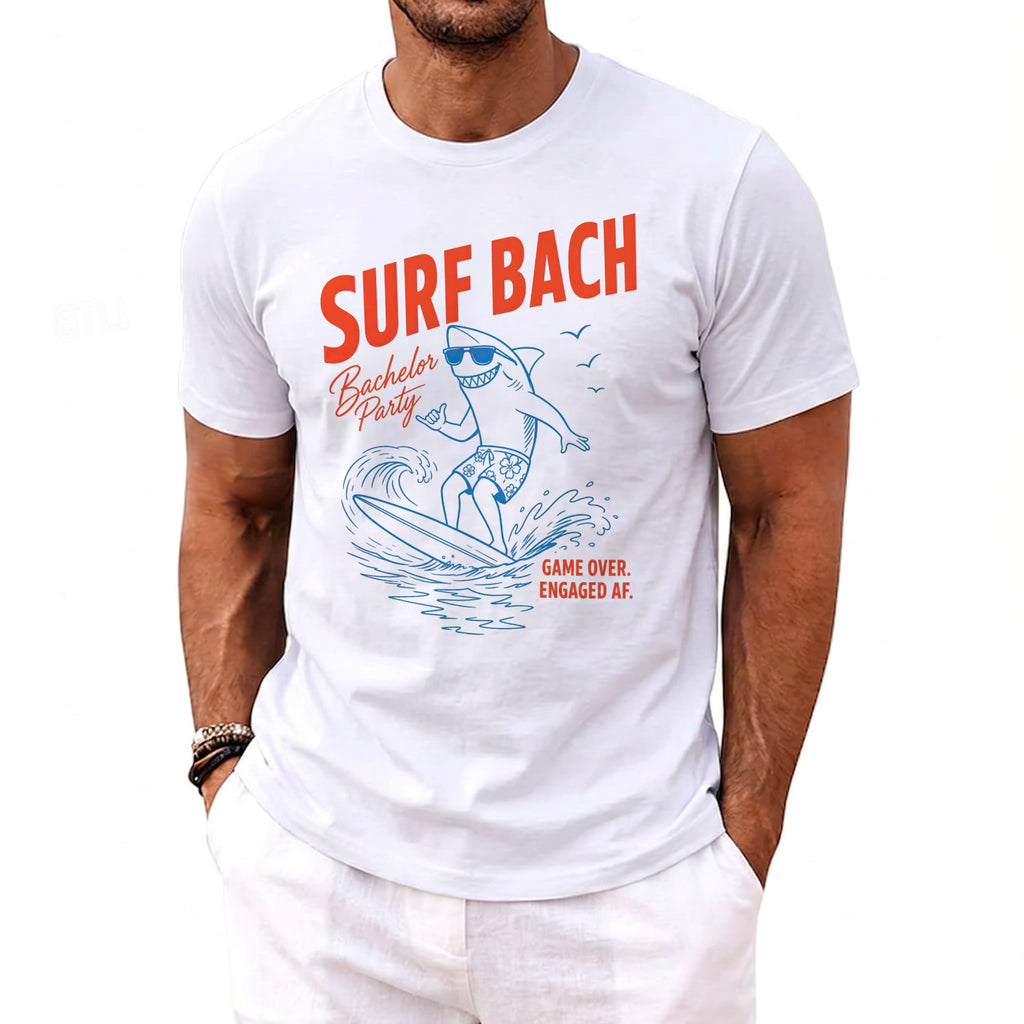 White t-shirt with "SURF BACH Bachelor Party" and a surfing shark design.