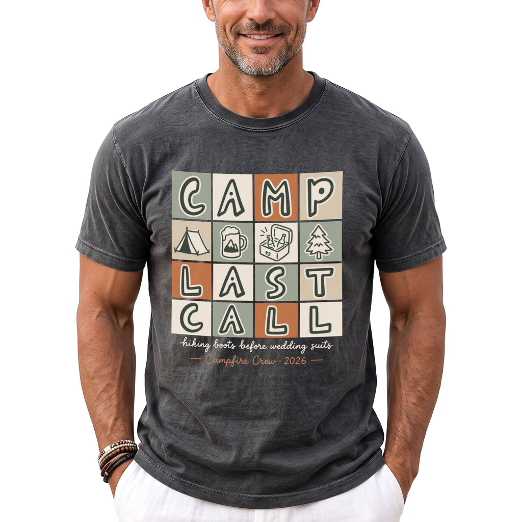 Dark gray t-shirt with "CAMP LAST CALL" and camping graphics, "hiking boots before wedding suits", "Campfire Crew 2026".