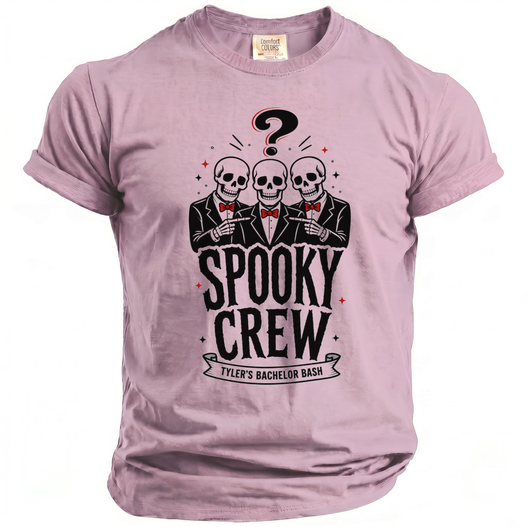 Pink t-shirt with a graphic of three skeletons in suits pointing, a question mark, and the text "SPOOKY CREW TYLER'S BACHELOR BASH".