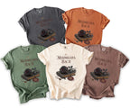 Five t-shirts in different colors with "Maximilian's Bach" and a rose on a book design.