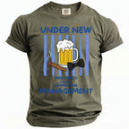Olive t-shirt with "Under New Management" text, beer, cigar, and bow tie graphic.