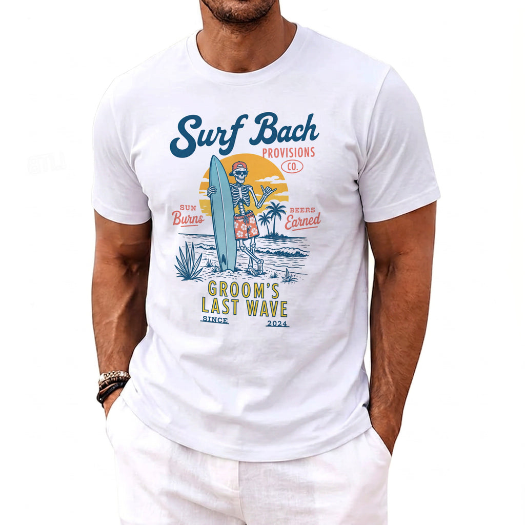 White t-shirt with a skeleton surfer graphic that reads "Surf Bach Provisions Co." and "Groom's Last Wave".