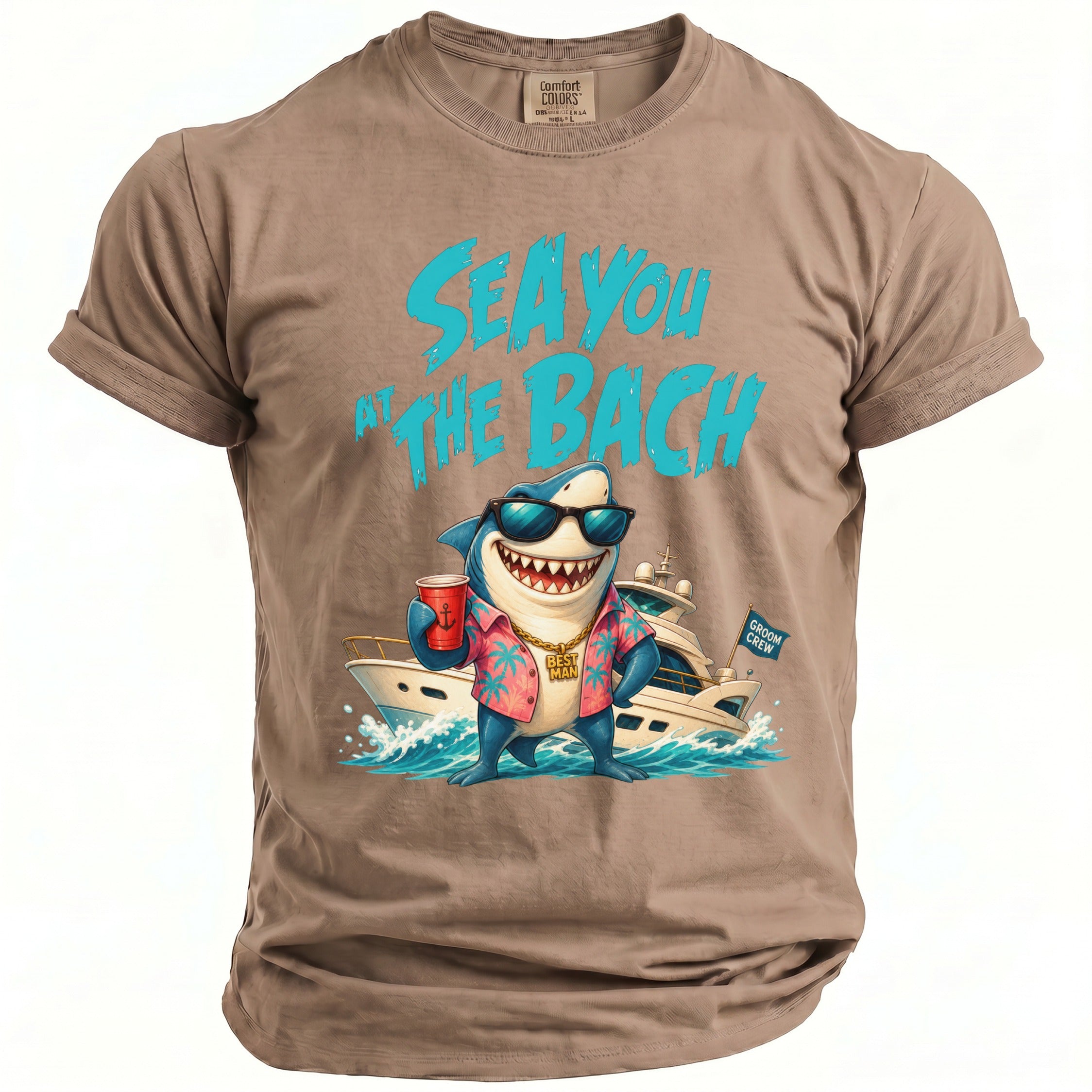 Tan t-shirt featuring a cartoon shark wearing sunglasses, a shirt, and a gold chain, holding a cup in front of a yacht, with blue text that reads "Sea You At The Bach".