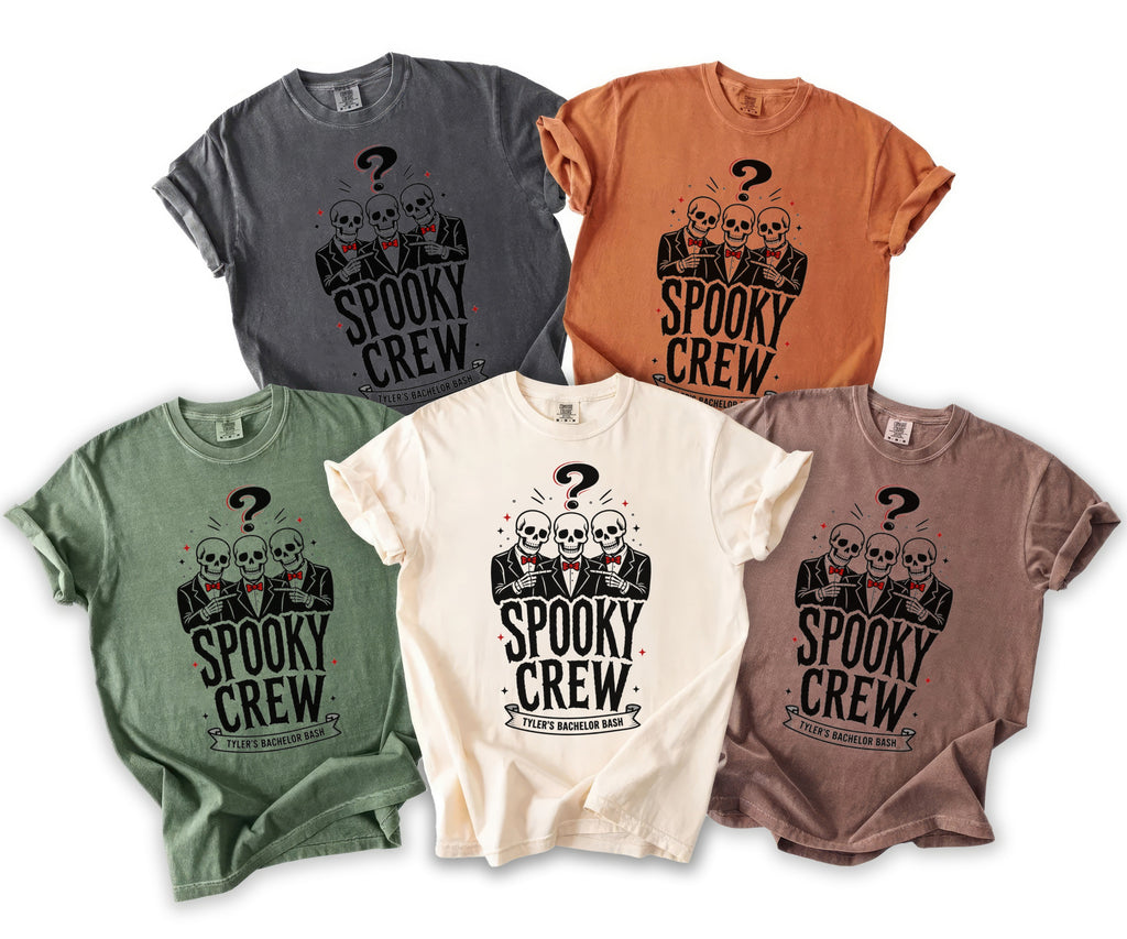 Multiple t-shirts in different colors featuring three skeletons in suits with "Spooky Crew" text.