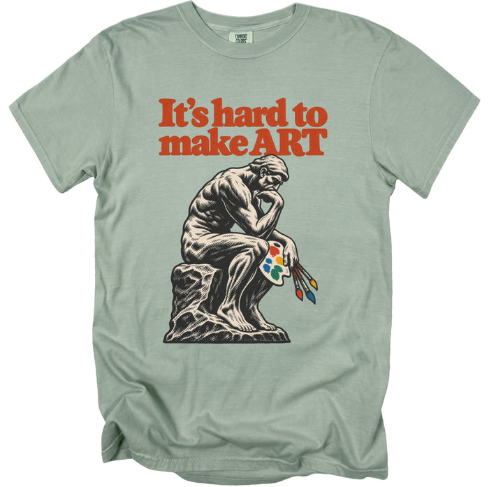 T-shirt with "It's hard to make ART" text and The Thinker statue holding art supplies.