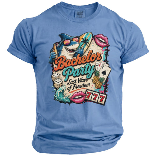 Blue t-shirt with Bachelor Party Last Wave of Freedom graphic: shark, surf, dice, cards, lips, and slot machine.